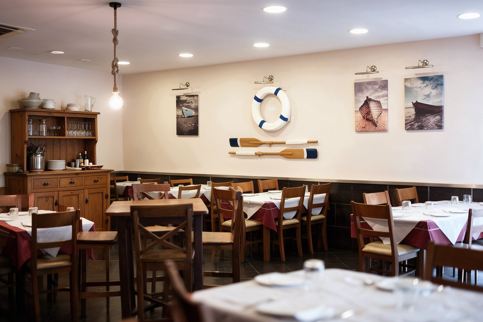 Comedor luminoso del Restaurante Casa Antonio con salvavidas en la pared y mesas servidas